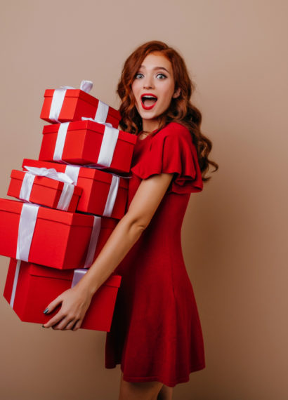 mulher em um vestido vermelho carregando caixas de presentes